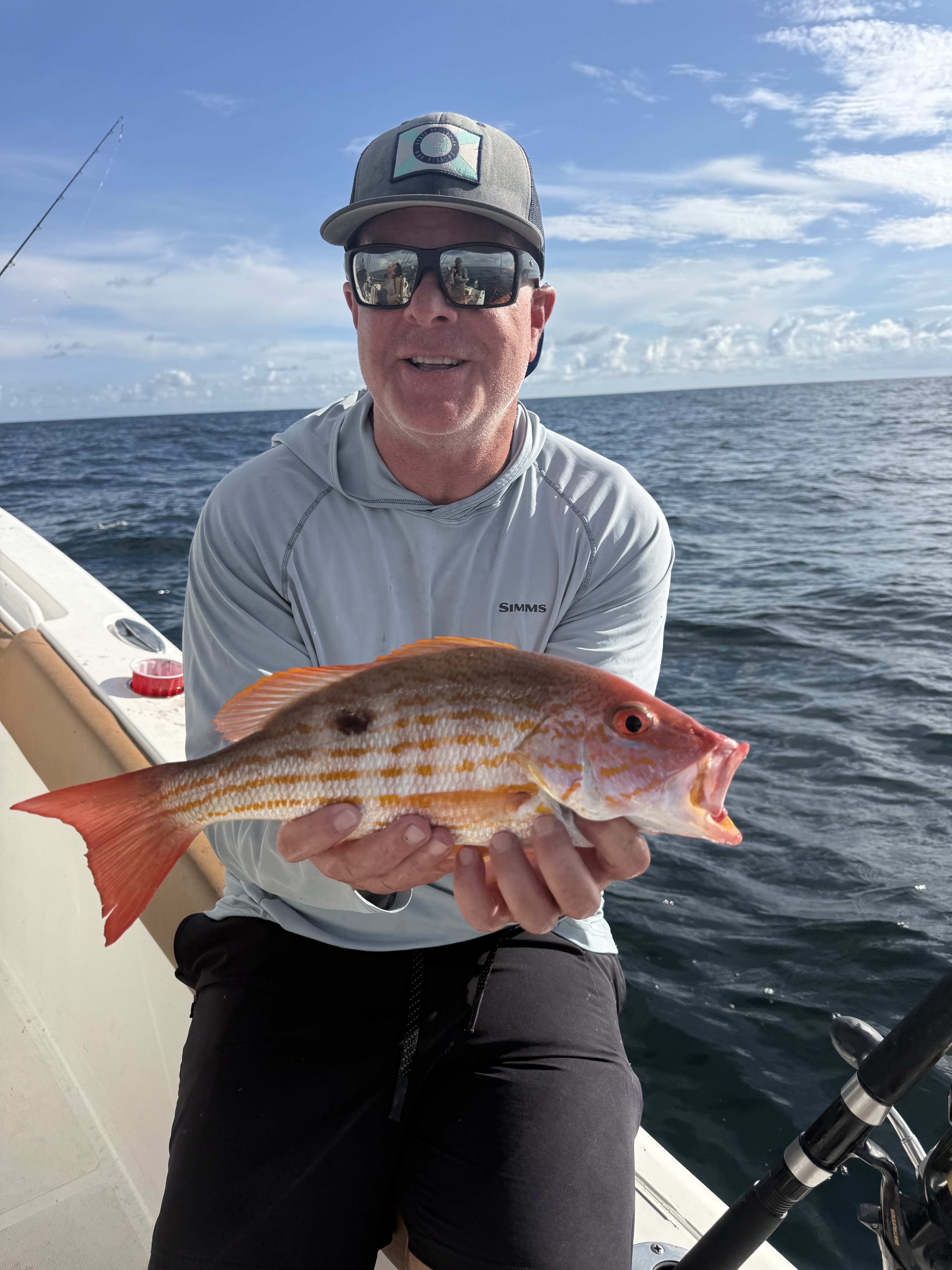 A customer holding a colorful snapper catch aboard the Big Fish Energy charter boat