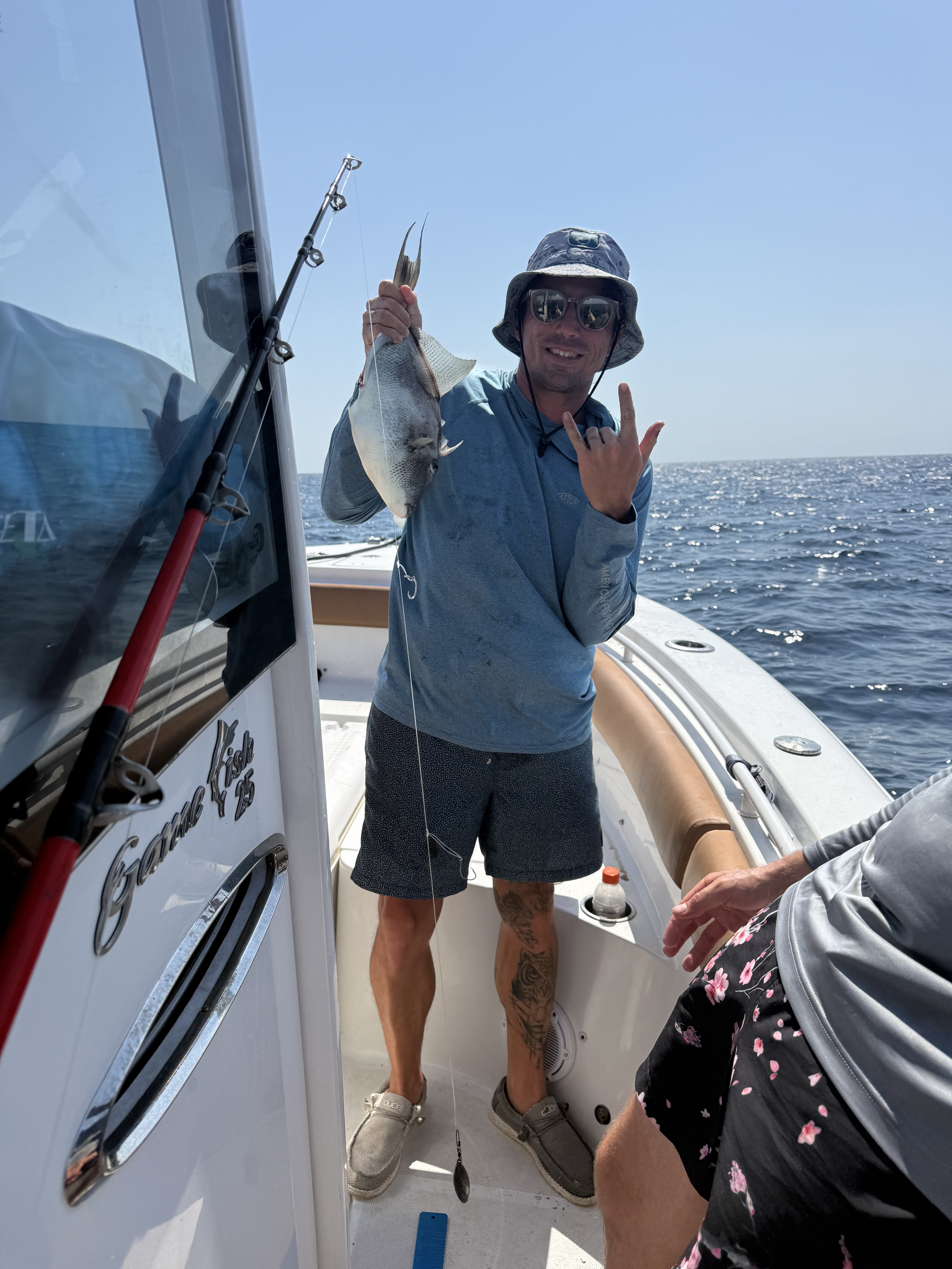 A customer holding up a triggerfish catch aboard the Big Fish Energy charter boat