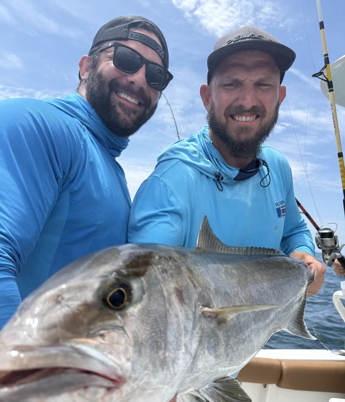 Captain Jon and first mate Ray holding up a big amberjack catch aboard the charter boat